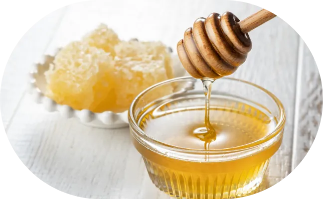 Honey dripping from a wooden dipper