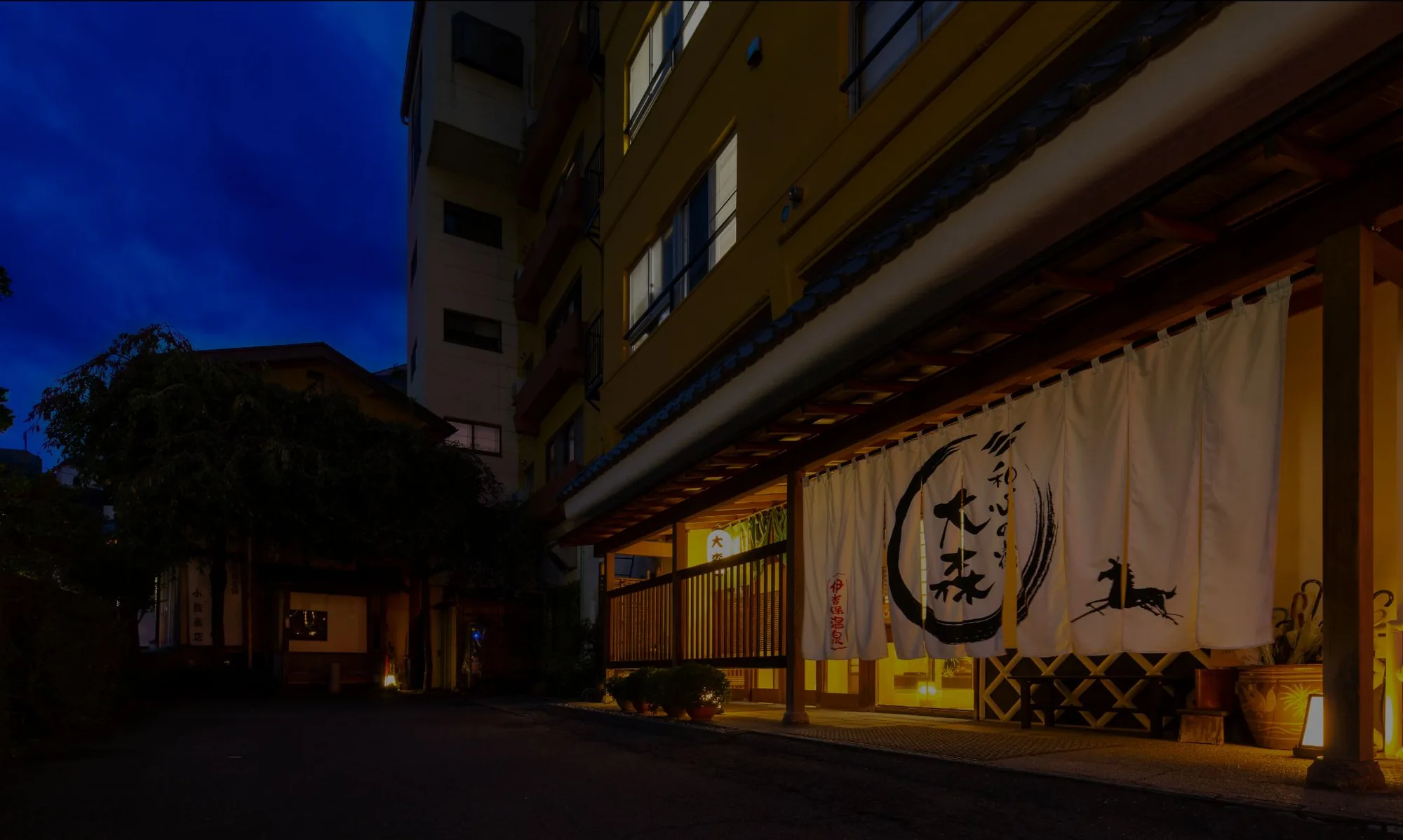 Twilight at the entrance of Ryokan Omori, with the noren and the horse crest